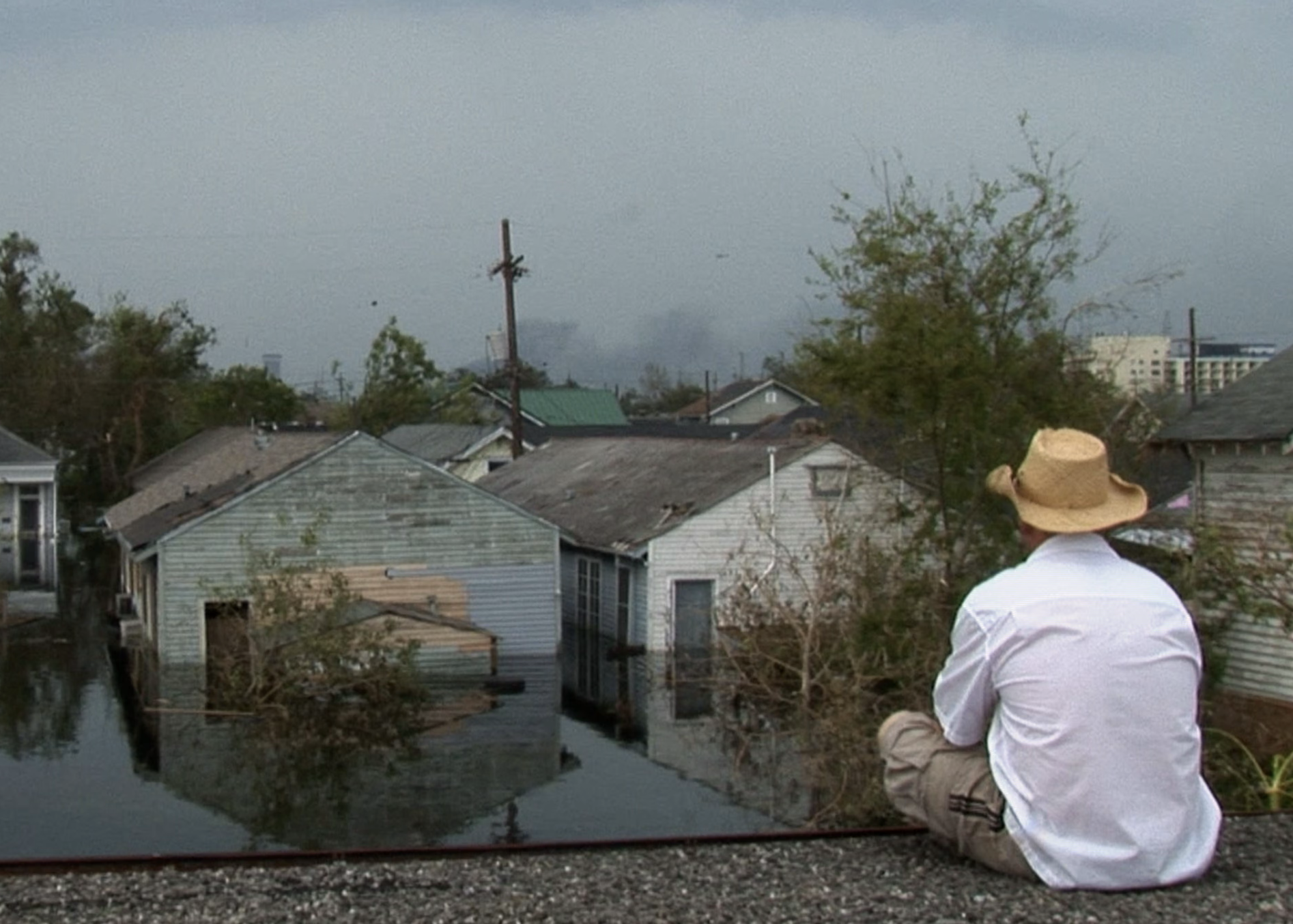 Photograph of a man looking out at flooded New Orleans. Credit: Wickes Helmboldt.